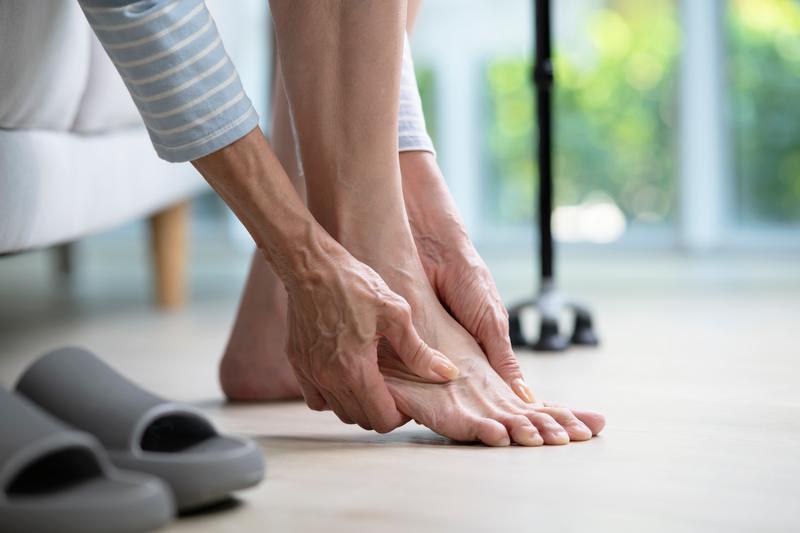 Foot pain concept, senior woman suffering from pain in ankle at home. woman rubbing, massaging sore feet area of pain, Mature woman discomfort painful feet ache from walking.